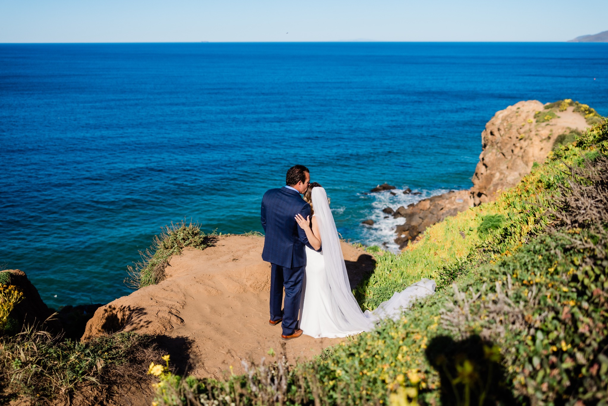 Sean and Mackaylee embracing beside the ocean in their wedding attire